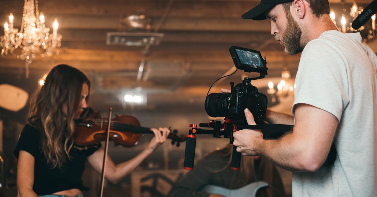 a close shot in music video (fisheye ? prob. not ) - Man Holding Camera and Woman Playing Violin