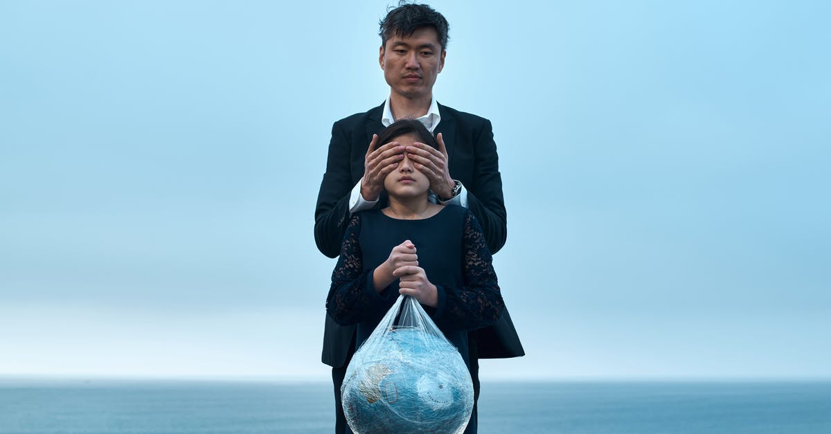 A movie about getting to a fake utopian planet / virtual environment [closed] - Asian male in formal wear standing near seashore and covering eyes of girl in black dress with Earth globe in plastic bag environment pollution concept