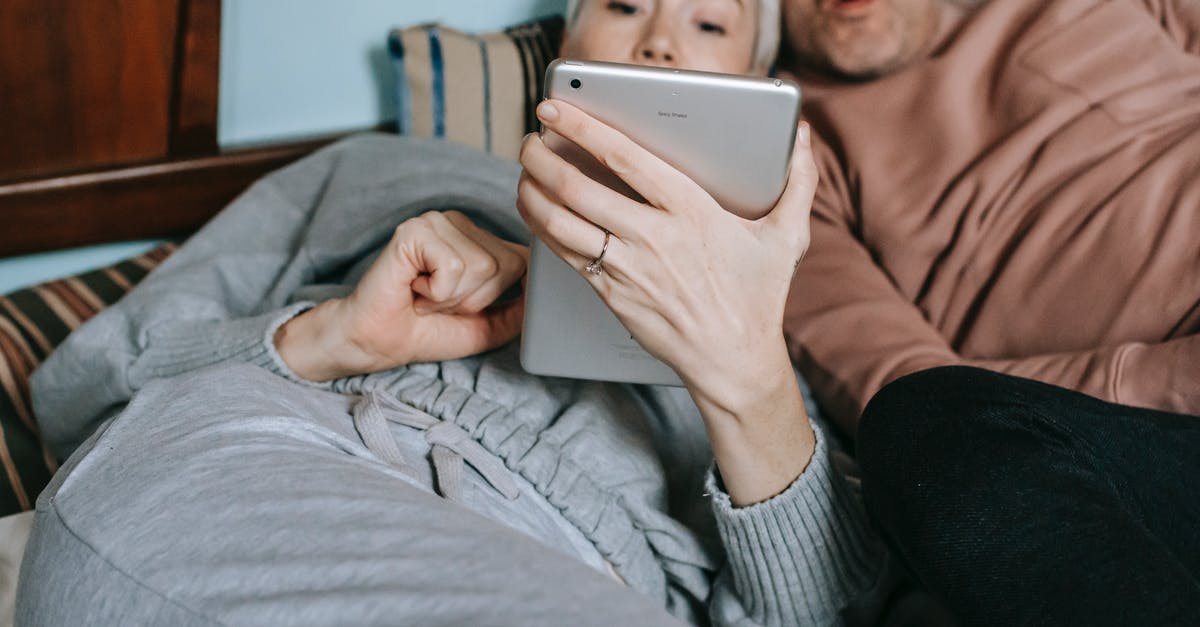 A movie with a time machine that is being used to stop a crime [closed] - Crop adult diverse married couple in casual clothes cuddling while lying on bed and watching interesting movie on tablet