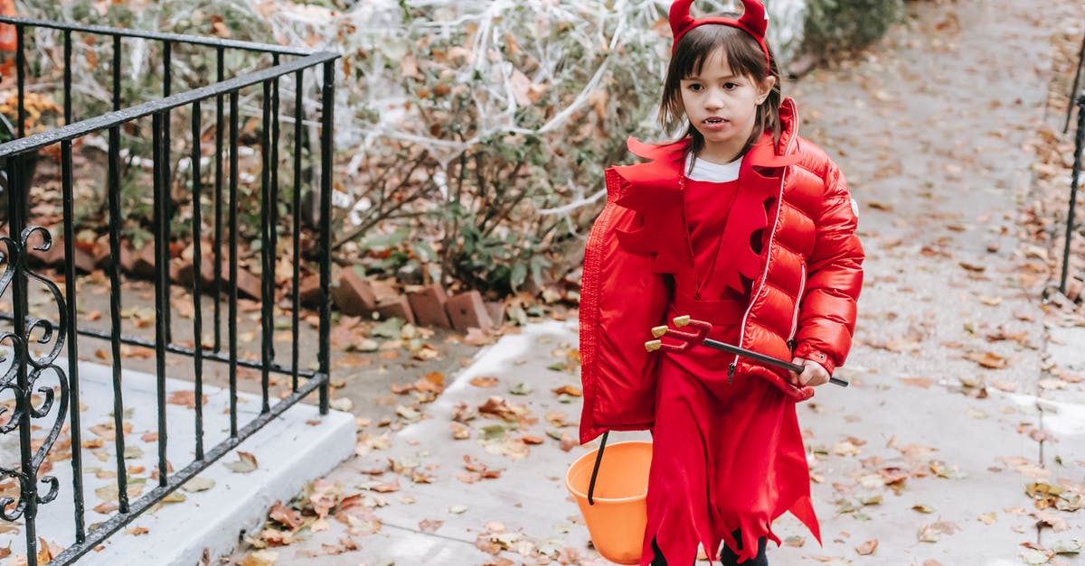 A Question about the little girl in red dress in Schindler's List - Little girl in red costume of devil for Halloween with horns and pitchfork walking on street in daytime in autumn