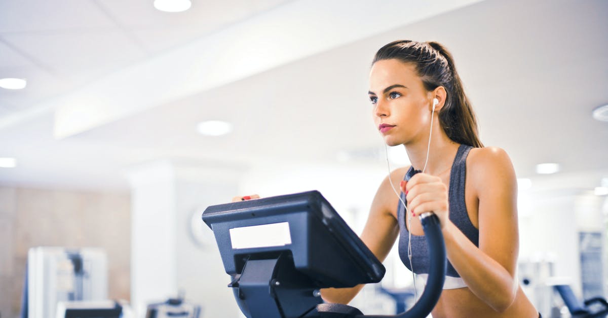 A woman gets turned into a man by a makeover machine [closed] - Serious fit woman in earphones and activewear listening to music and running on treadmill in light contemporary sports center