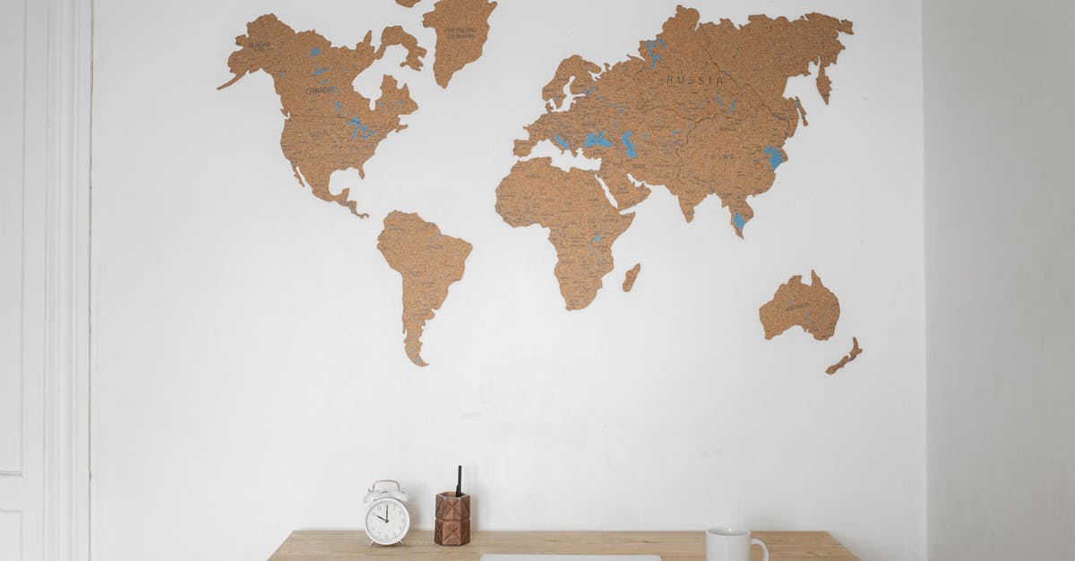 Adjusted Worldwide Box Office - Alarm clock near pen container with cup and laptop on table placed near silhouettes of world map on wall