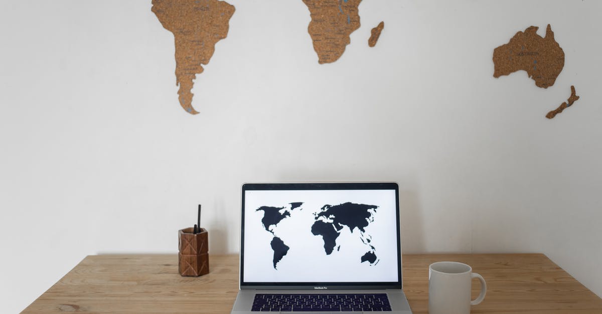 Adjusted Worldwide Box Office - Black world map on laptop screen and ceramic cup with pen container placed on table against silhouettes of continents
