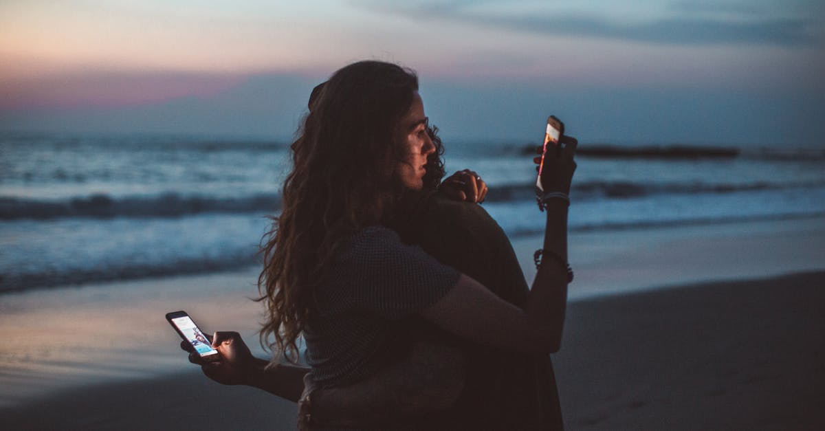 Adolf Hitler using the technology in the phone to win a war? - Couple hugging and using smartphone near sea on sunset