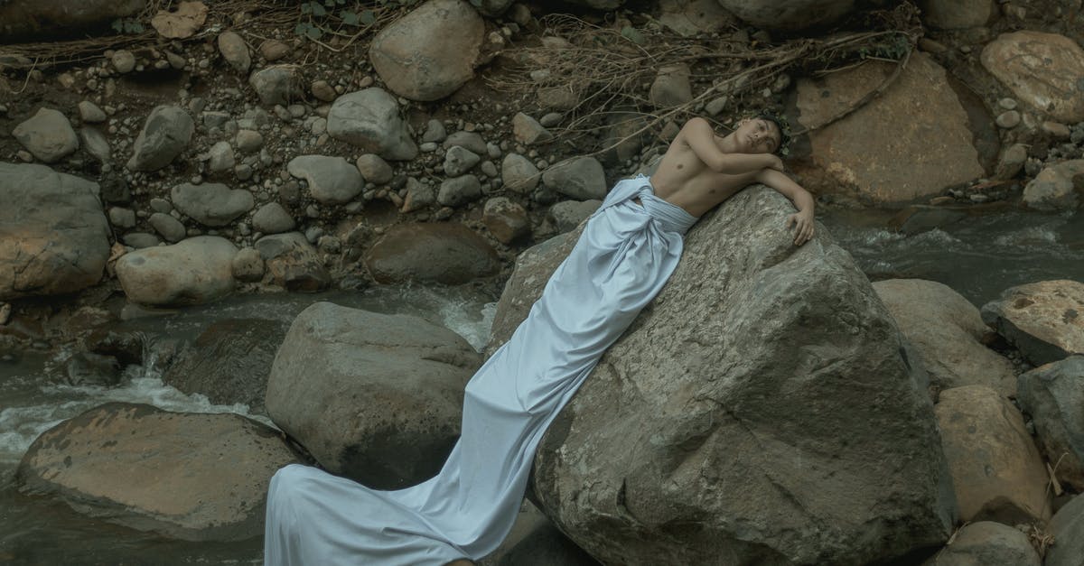 Ancient mythology and black-goo in Prometheus - Male in long white sheet resting on heavy rough stone near splashing stream
