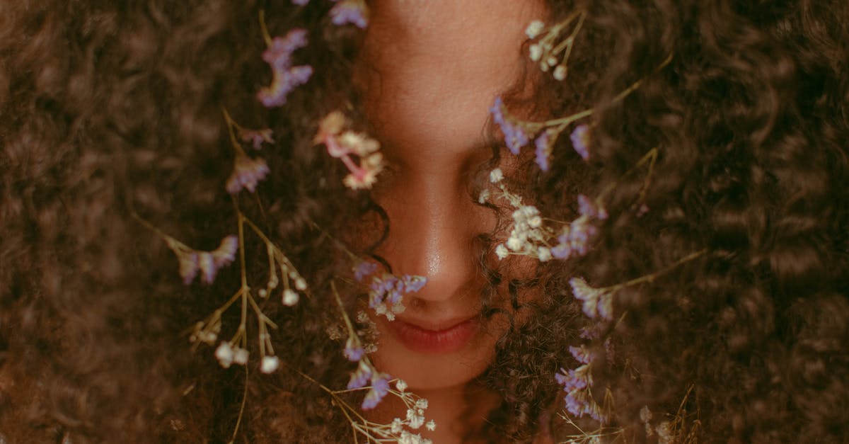 Appearance of a boggart to someone who is most afraid of boggarts - Headshot of anonymous content female with small bright flowers with white and purple petals tangled in brown hair covering face