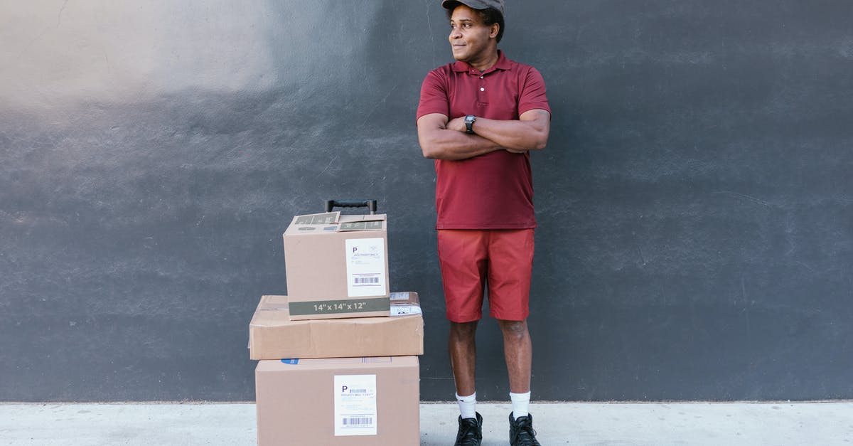 Are all JMC ships red? - Man in Red Polo Shirt and Red Pants Standing Beside Brown Cardboard Boxes