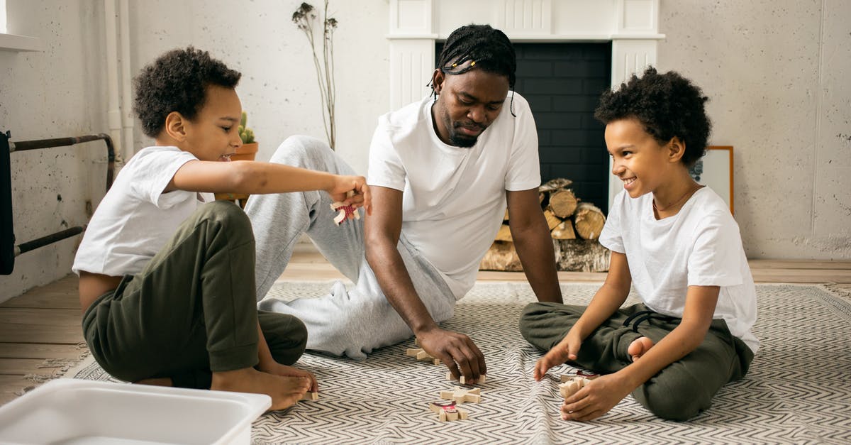Are Ray and Emmit Stussy twin brothers? - Full body of cheerful African American twin brothers in similar casual clothes smiling while sitting on floor and playing with toys together with happy young father