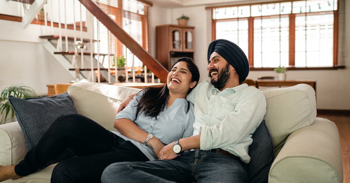 Are shows with laugh tracks considered a lower form of comedy by the TV industry? - Laughing young Indian couple watching comedy movie together at home