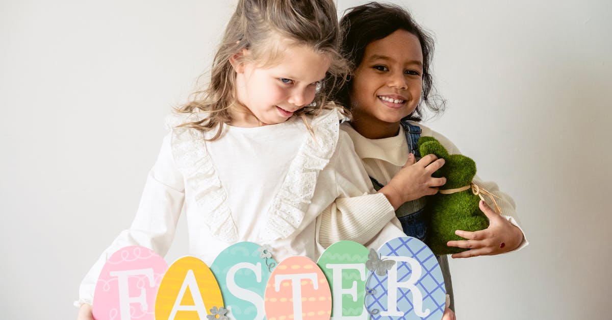 Are there any hints about the content of the Hollyhock letter? - Joyful diverse girls with bunny and decorative wooden eggs with letters standing on white background during Easter celebration in room