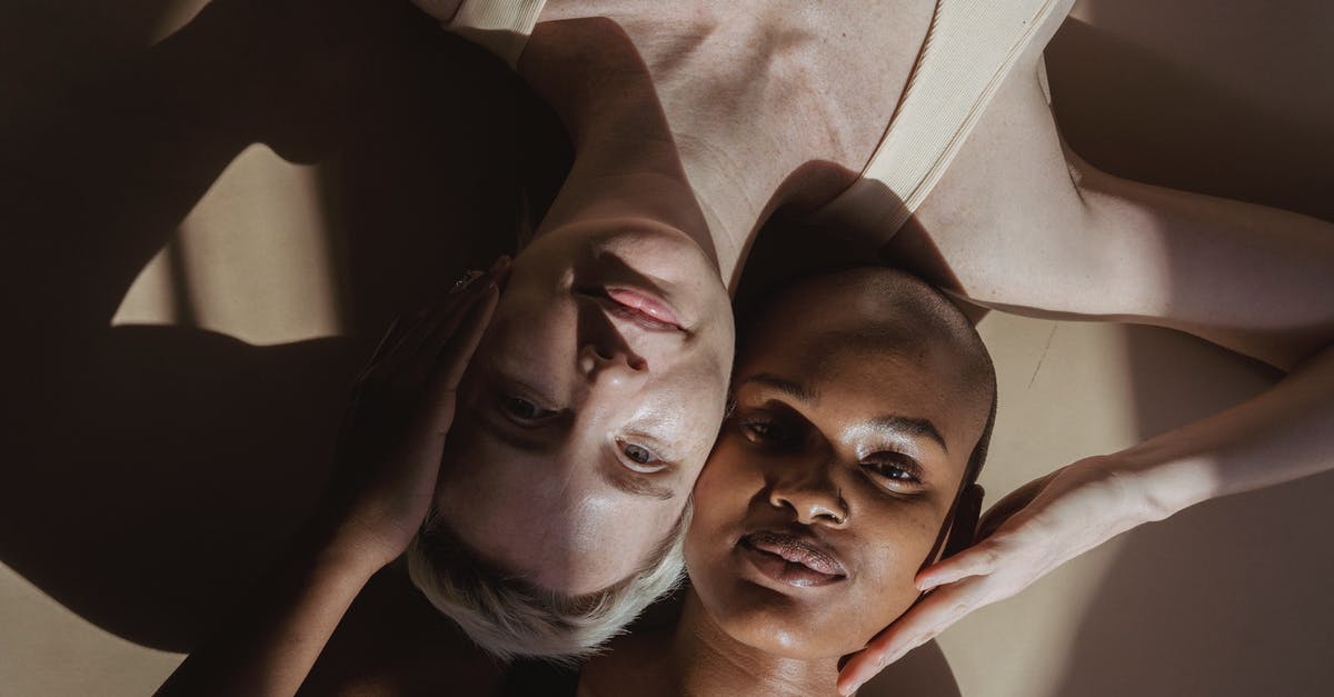 Are there different versions of Aronovsky's Black Swan? - Top view of smiling multiethnic female models without makeup lying on gray surface and touching heads holding hands on face while looking at camera with shadows on face