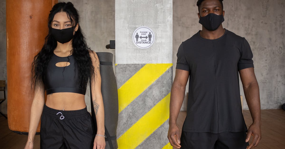 Are they going to reveal how the virus spread and who made it? - Young diverse female and African American male in protective masks standing at distance and looking at camera