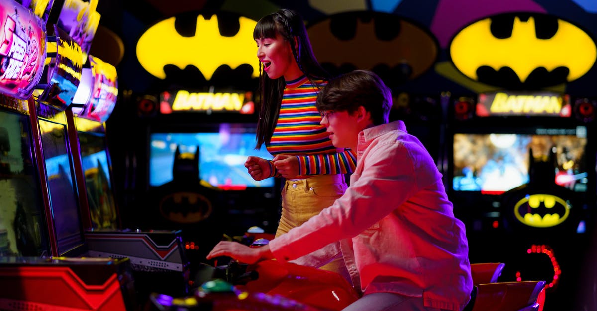 Batman is what? - Woman Supporting the Man Playing Arcade Game
