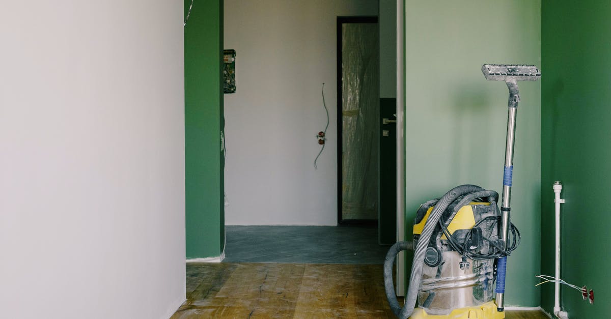 Benedict replaced the floor in the vault - Industrial vacuum cleaner placed on dirty parquet in room with green walls and doorway in spacious apartment during repair works