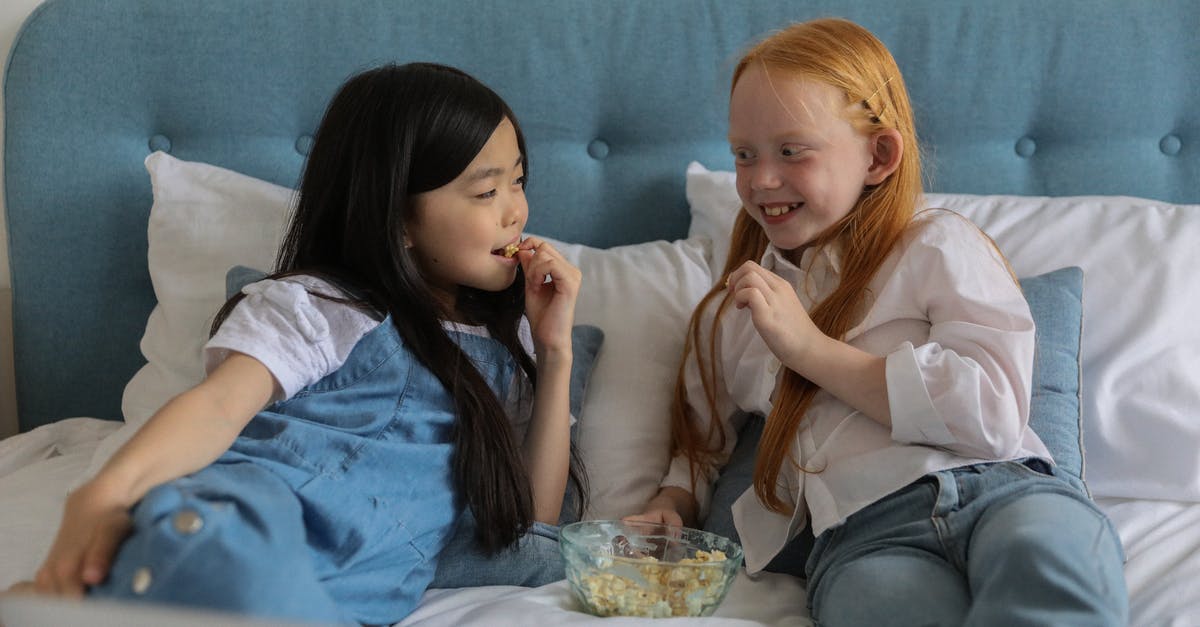 Best order to watch the Underworld movie series - Happy little multiethnic children with dark and red hairs lying on comfortable bed and looking at each other while eating popcorn during lazy weekend