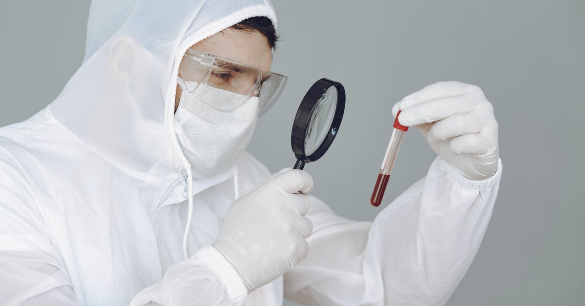 Blood on the lens - Person Wearing Personal Protective Equipment While Holding Magnifying Glass and Test Tube