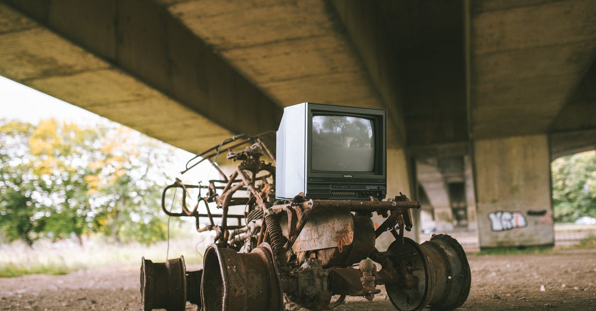 Bridge unsuccessfully destroyed in "A Bridge Too Far" - Old damaged vehicle with vintage television set on rough pathway under bridge in sunlight