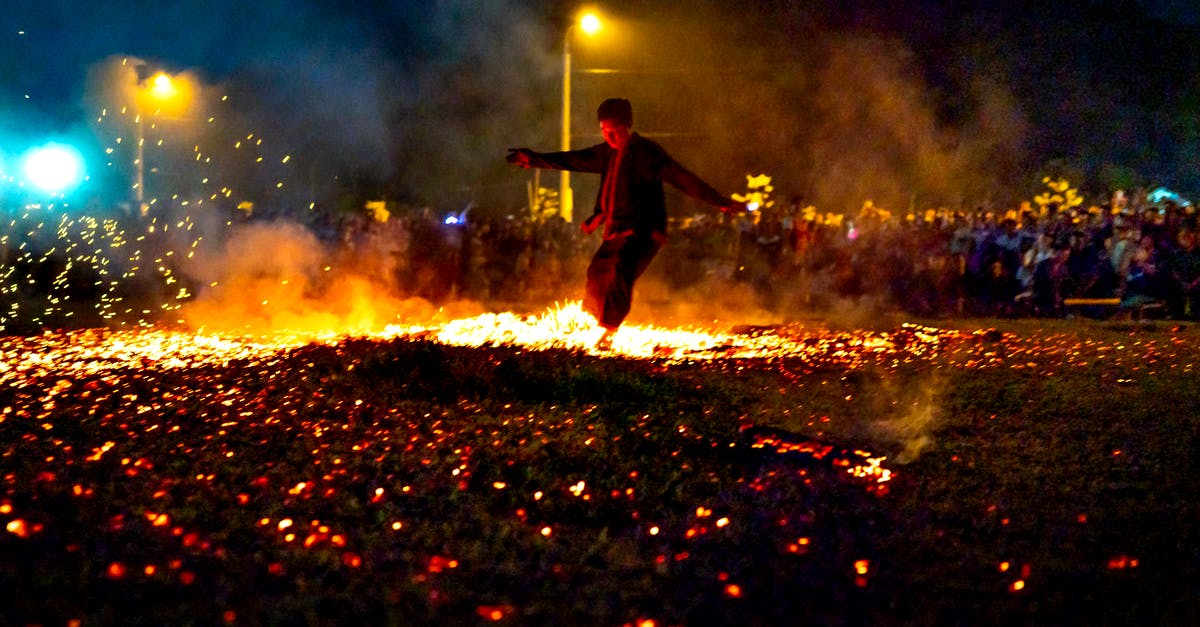 Camera technique where crowd moves fast around a stationary character? - Full body of unrecognizable male running on hot burning coals during show in evening time