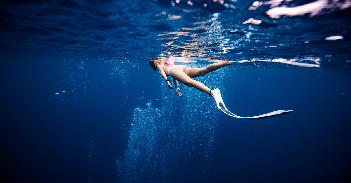 Can Allen survive under the water without oxygen? - Female diver in swimwear and flippers swimming on surface of deep blue ocean