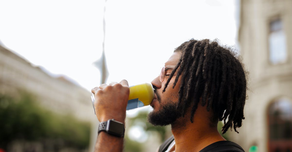 Can anyone help me find this sci-fi/horror movie with guys backpacking and an invisible alien? [closed] - Side view of adult Hispanic guy with dreadlocks in sunglasses and casual clothes with backpack and smart watch drinking yummy beverage from vivid yellow can while standing with eyes closed on street in downtown