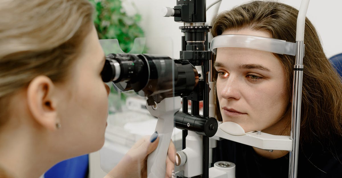 Can Loki control Vision? - Concentrated female medical specialist using professional tool for checking vision of patient in contemporary ophthalmology clinic