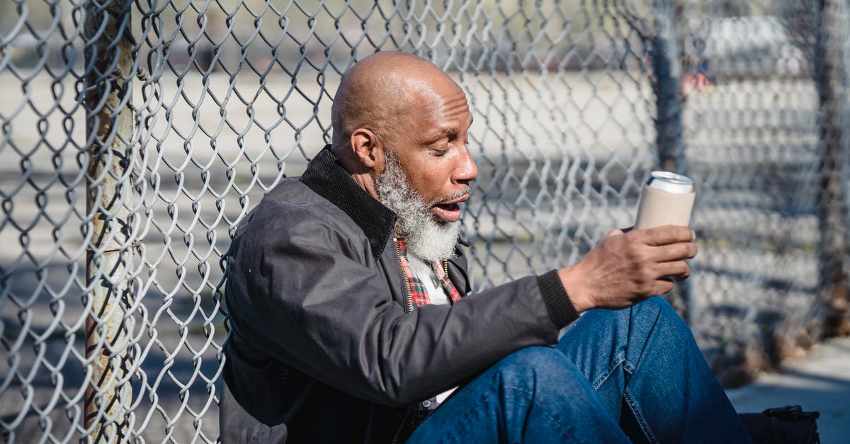 Can The Wolverine be viewed as a stand-alone film? - Side view of black homeless bald man sitting on street with beer can in hand and leaning on wire railing