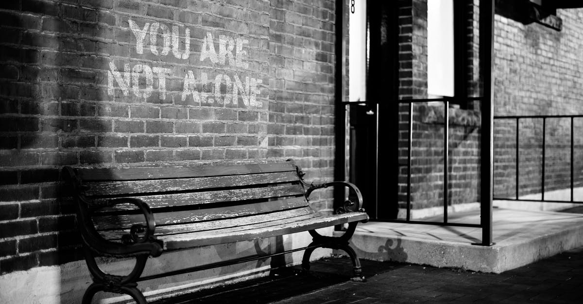 Can this quote from The Fifth Estate be attributed to Julian Assange? - Black and white of empty wooden bench near brick wall of building with inscription you are not alone