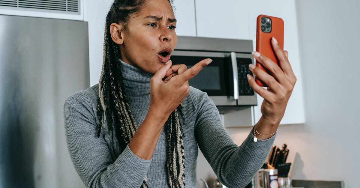 Confusing plot point in The Sense of an Ending - Angry young African American female with long braids in casual clothes pointing at screen nervously while disputing during video call on mobile phone in kitchen