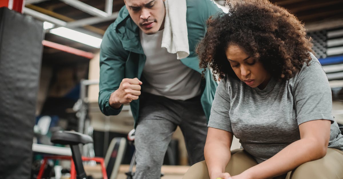Could a fire hose really support the weight of a falling man? - From below of strong personal coach explaining black woman how to exercise with dumbbells properly