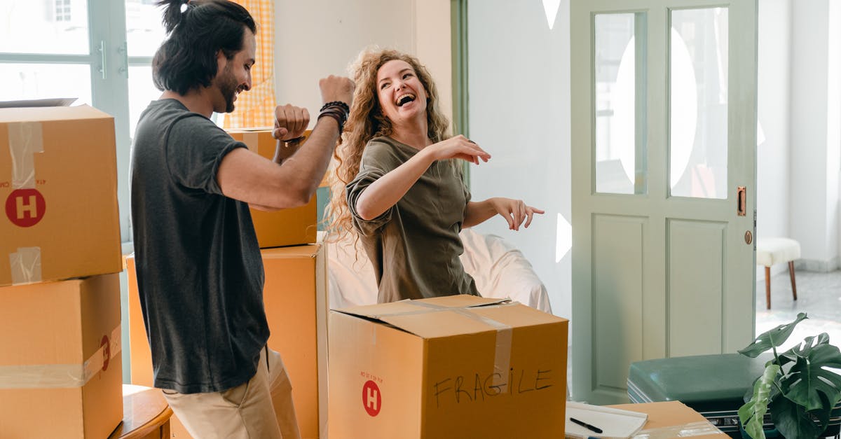 Dead wife haunting her husband's new wife [closed] - Cheerful laughing couple in casual clothes having fun and dancing together while unpacking carton boxes after moving into new contemporary apartment