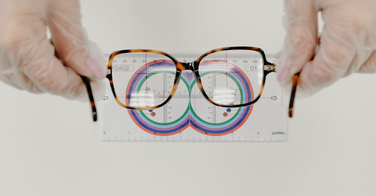Description of A Series of Unfortunate Event's visual style - From above of crop anonymous oculist in sterile gloves measuring modern eyewear with optical tool on white background