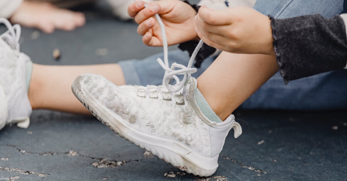 Did Cleo purposefully try to sabotage Beth? - Unrecognizable child with bent leg tying laces on dirty footwear while sitting on playground on street with anonymous kid on blurred background