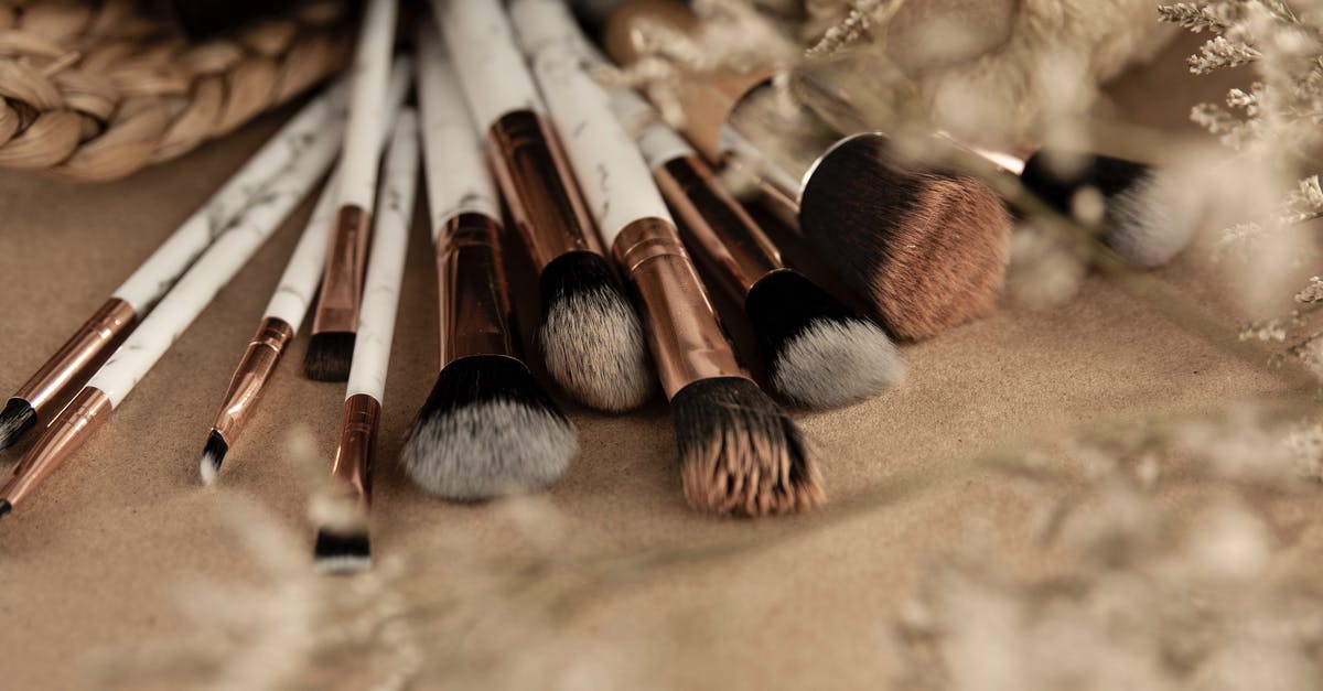 Did cunnilingus actually happen in Basic Instinct? - Clean makeup brushes spread out on beige table near wicker basket with eyeshadow and dried grass