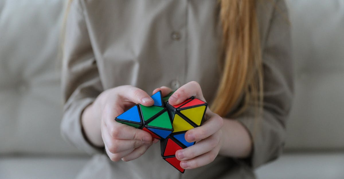 Did Emma Russel change her mind about her initial plan? - Crop anonymous girl demonstrating and solving colorful puzzle with triangles in soft focus