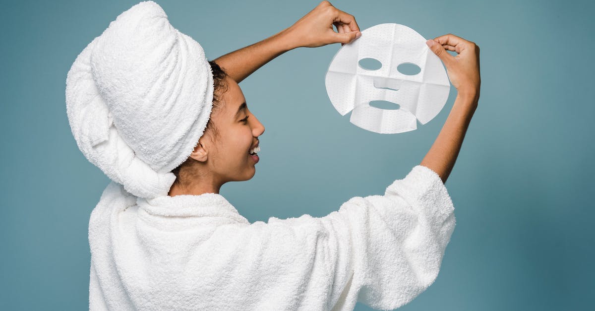 Did Hannah Wells' have a 'story'? - Back view of happy young African American female in bathrobe with towel on head smiling while demonstrating skin care mask against blue background