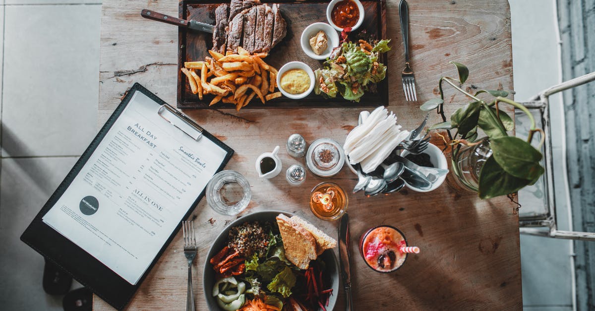 Did Mary really attend the French class? - Top view of wooden table with salad bowl and fresh drink arranged with tray of appetizing steak and french fries near menu in cozy cafe