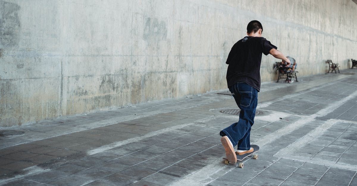 Did the young boy move the broom through the Force? - Full body of faceless teenage skater in casual outfit practicing skateboard riding on paved street