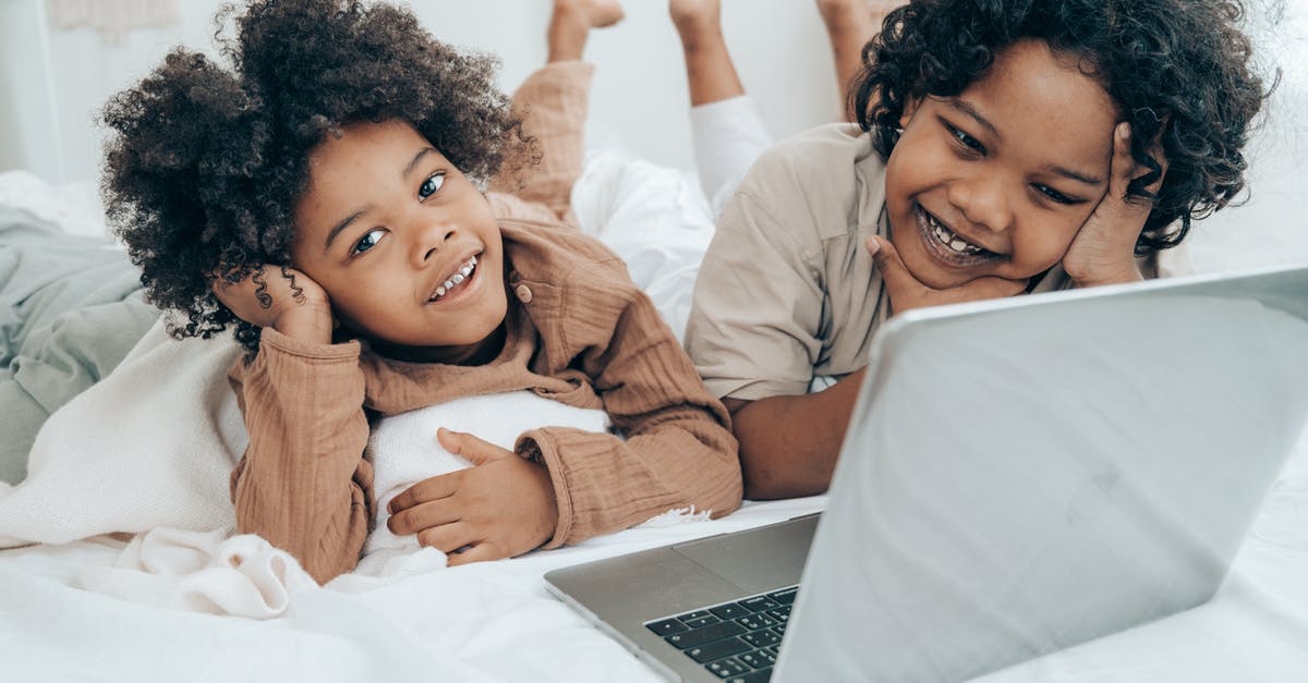 Digital Movies, DVD's and the law - Smiley black boys watching funny video on laptop on bed