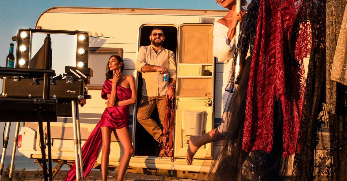 Do film industries outside India use intervals/Intermission? - Full body of cheerful male standing in trailer near gorgeous women wearing stylish dresses on street with collection of outfits on rack and professional supply while preparing for video shoot
