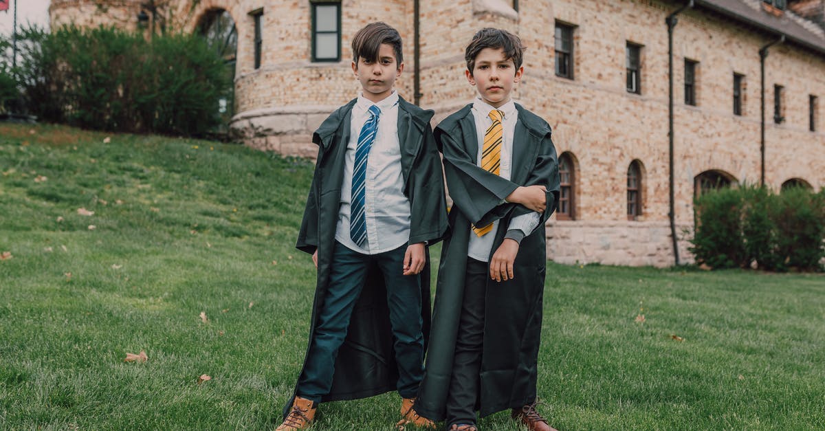 Do Harry Potter scarves in the movies have house emblems? - Boys Wearing Black Coats while Standing Near the House with Stone Walls