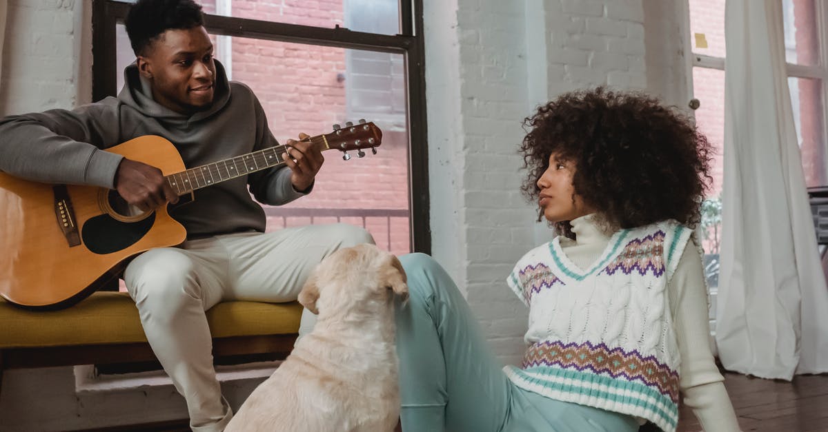 Do other-language dubs rerecord sound effects? - Cheerful black man playing guitar for girlfriend and dog at home