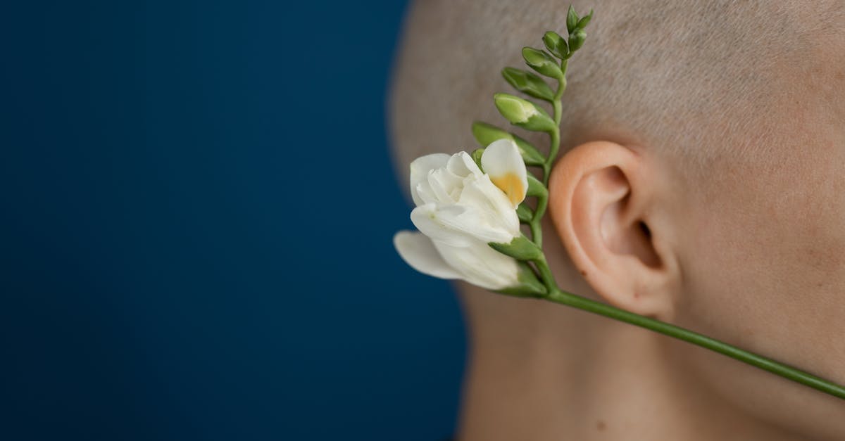 Do patients experience tastes during brain surgery? - Side view of crop unrecognizable person with shaved head and blossoming flower representing cicatrice after brain tumor operation