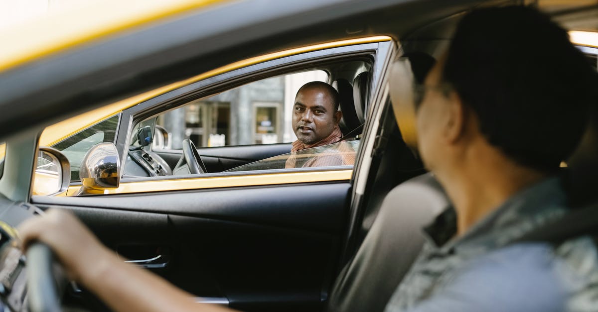 Do the Peaky Blinders speak Shelta or Romani to the Lees? - Side view of adult ethnic male cab driver interacting with anonymous colleague driving auto while looking at each other in city