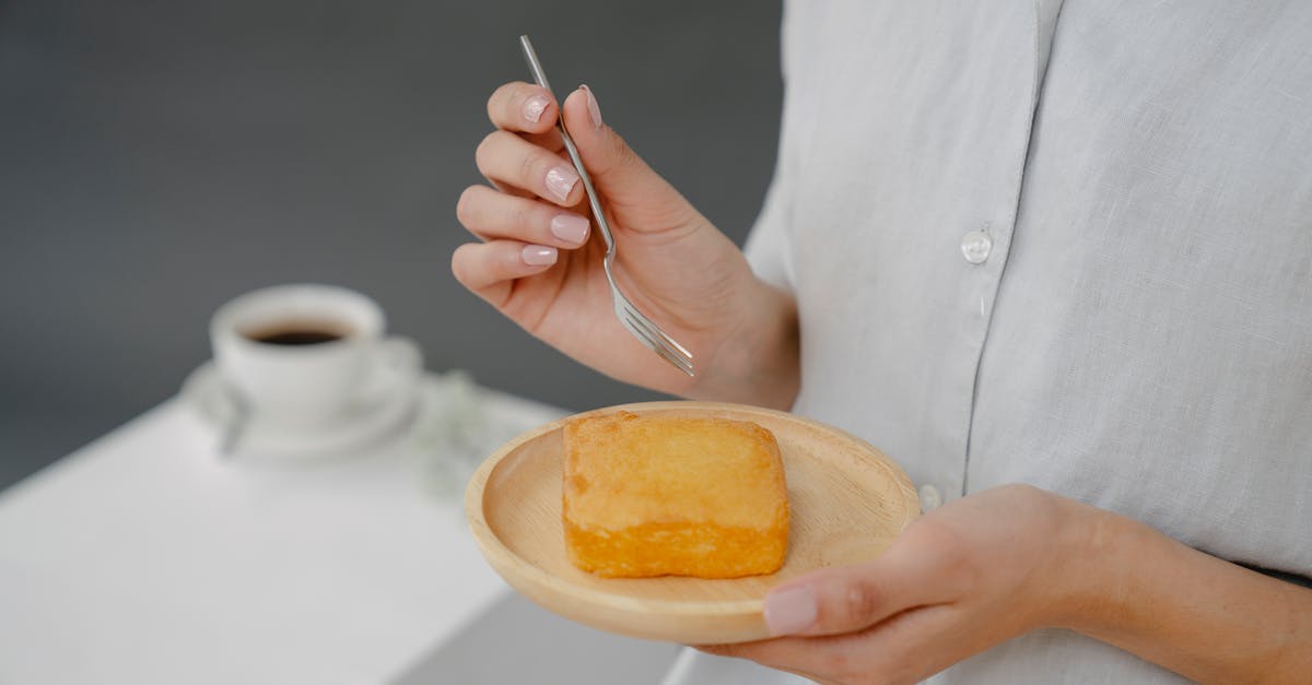 Do they really drink or eat when shooting movies? - Soft focus of crop faceless female with tasty fresh butter cake on plate standing on gray background in studio with cup of coffee