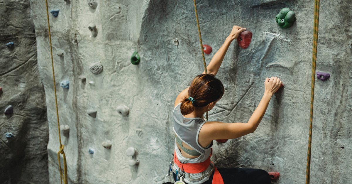 Do Wonder Woman's bracelets have special powers? - From above of anonymous female climber in activewear with special equipment climbing on climbing wall in gym