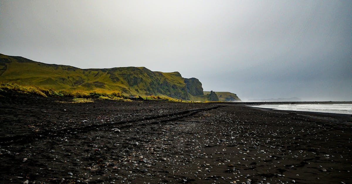 Does Black rock island keep changing with the sky? - Black Sand Shore Near Green Grassy Hill