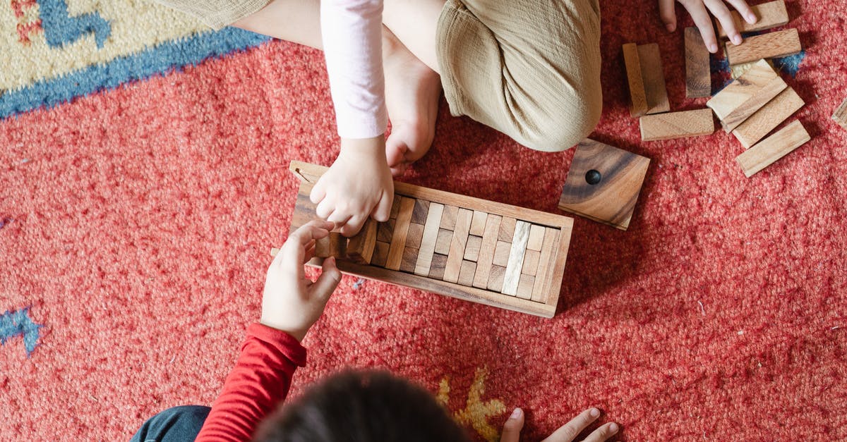 Does Brick Heck from The Middle have Asperger syndrome? - Top view of anonymous barefoot boy and girl in casual clothes sitting on floor carpet and playing with wooden blocks of jenga tower game