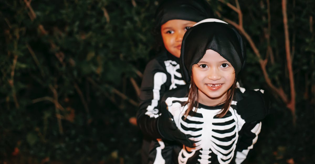 Does Dark have an ending? - Happy diverse girls in skeleton costumes  and masks on heads embracing while having fun and smiling in Halloween night in park