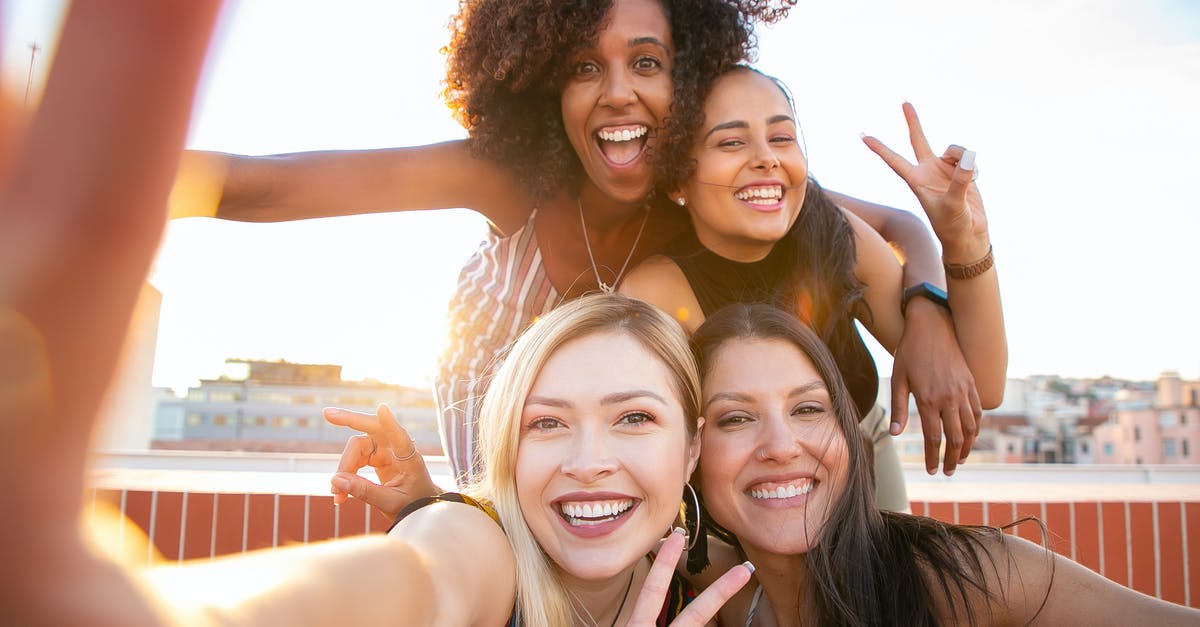 Does Dr No have all his fingers? - Cheerful young diverse women showing V sign while taking selfie on rooftop