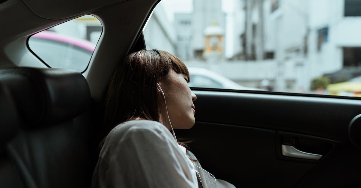 Does Glee use excessive auto tune? - Side view of unemotional female in white shirt resting in car passenger seat and listening to music via earphones while riding in urban environment
